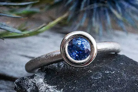 Besonderer Verlobungsring aus Platin mit einem Saphir in eismatt mit Donutfassung. Der Verlobungsring kann natürlich auch als Vorsteckring zum Ehering gesteckt werden